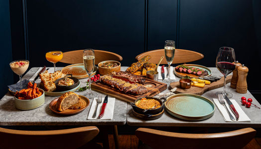 side shot of the big table populated with various meat dishes from Kindling menu
