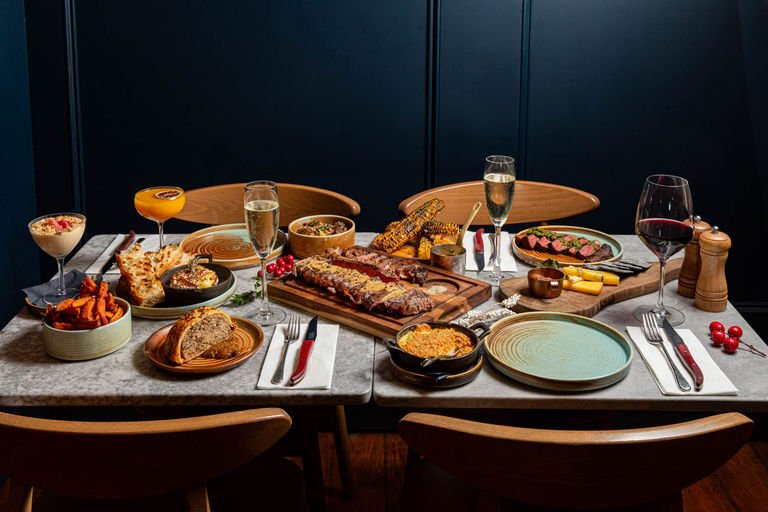 side shot of the big table populated with various meat dishes from Kindling menu