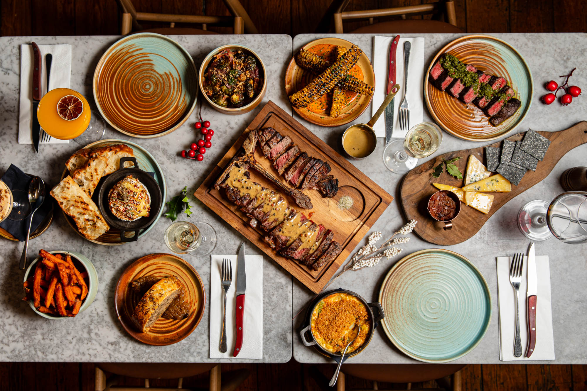 over head shot of the table populated with various meat dishes from Kindling menu including steaks