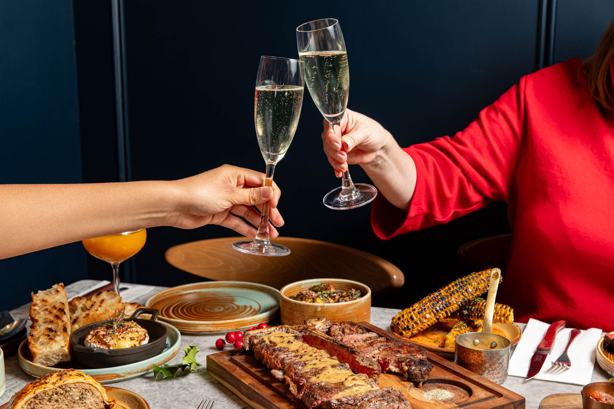 two people having a toast with champagne over the delicious food at Kindling Brighton