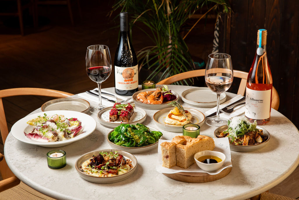 Lost in the Lanes: table filled out with various dishes and bottles of wines