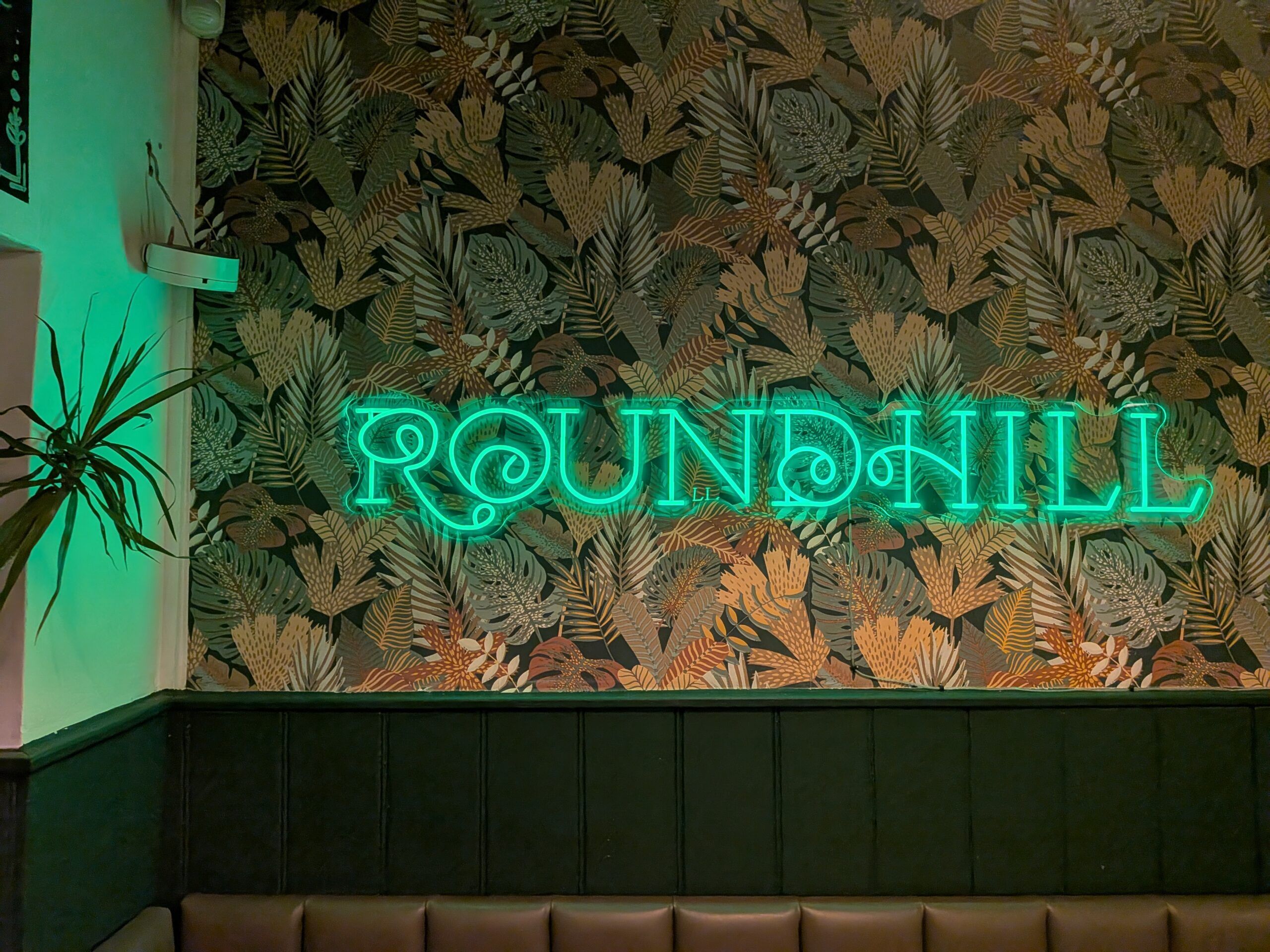 neon logo sign on the wall at The Roundhill Pub