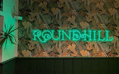 neon logo sign on the wall at The Roundhill Pub