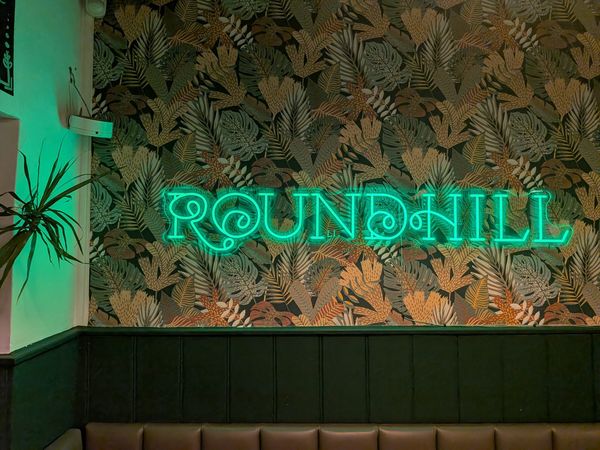 neon logo sign on the wall at The Roundhill Pub
