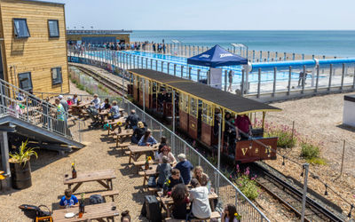 The Volks railway runs through the site where swimmers enjoy the opening day of Sea Lanes - the UK's first National Open Water Swimming Centre . At the heart of Sea Lanes Brighton is a 50m 6 lane outdoor pool located on the beach with local fitness, wellbeing, food, and beverage businesses creating a hub of units from sun up to sundown on the seafront in Kemp Town, Brighton ***Pic by David McHugh / Brighton Pictures 07768 721637***
