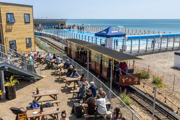 The Volks railway runs through the site where swimmers enjoy the opening day of Sea Lanes - the UK's first National Open Water Swimming Centre . At the heart of Sea Lanes Brighton is a 50m 6 lane outdoor pool located on the beach with local fitness, wellbeing, food, and beverage businesses creating a hub of units from sun up to sundown on the seafront in Kemp Town, Brighton ***Pic by David McHugh / Brighton Pictures 07768 721637***