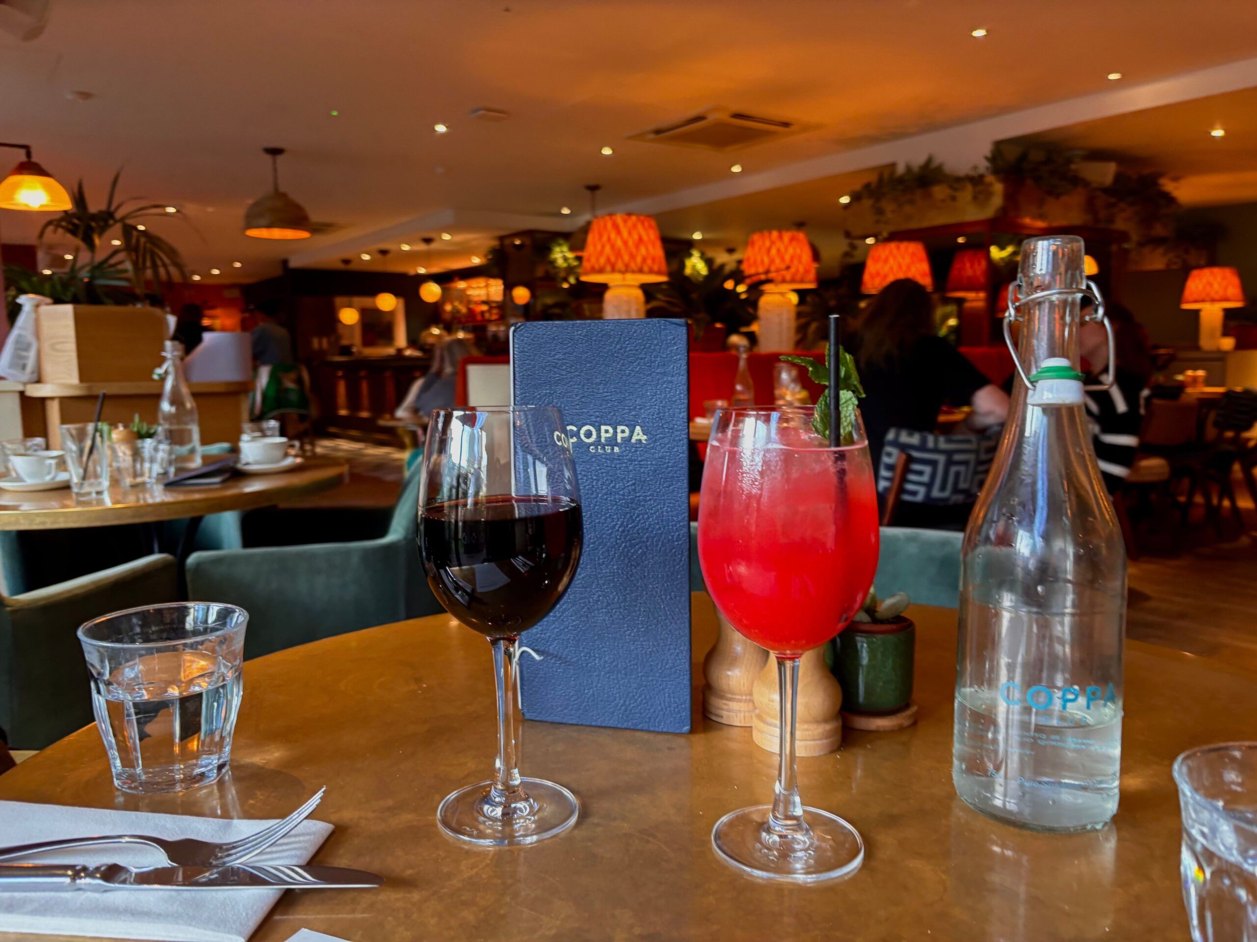 glass of red wine and Pomegranate & Pear Hugo Sprit, served on the wooden table at coppa club