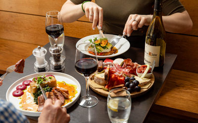 two people dining at Petit Pois, two dishes and charcoal board on the table with bottle and glasses of wine