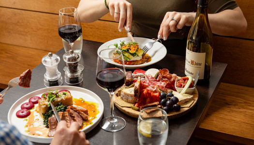 two people dining at Petit Pois, two dishes and charcoal board on the table with bottle and glasses of wine