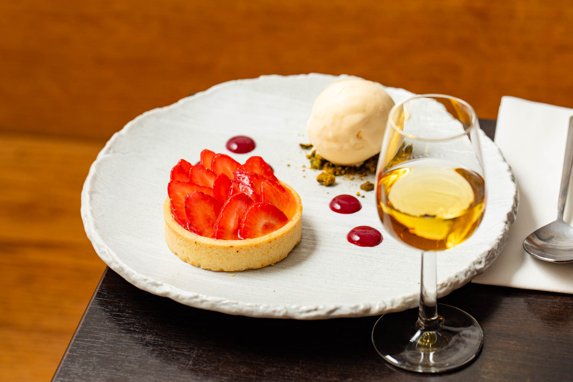 strawberry tart with ice cream scoop on the white plate served with glass of alcohol drink