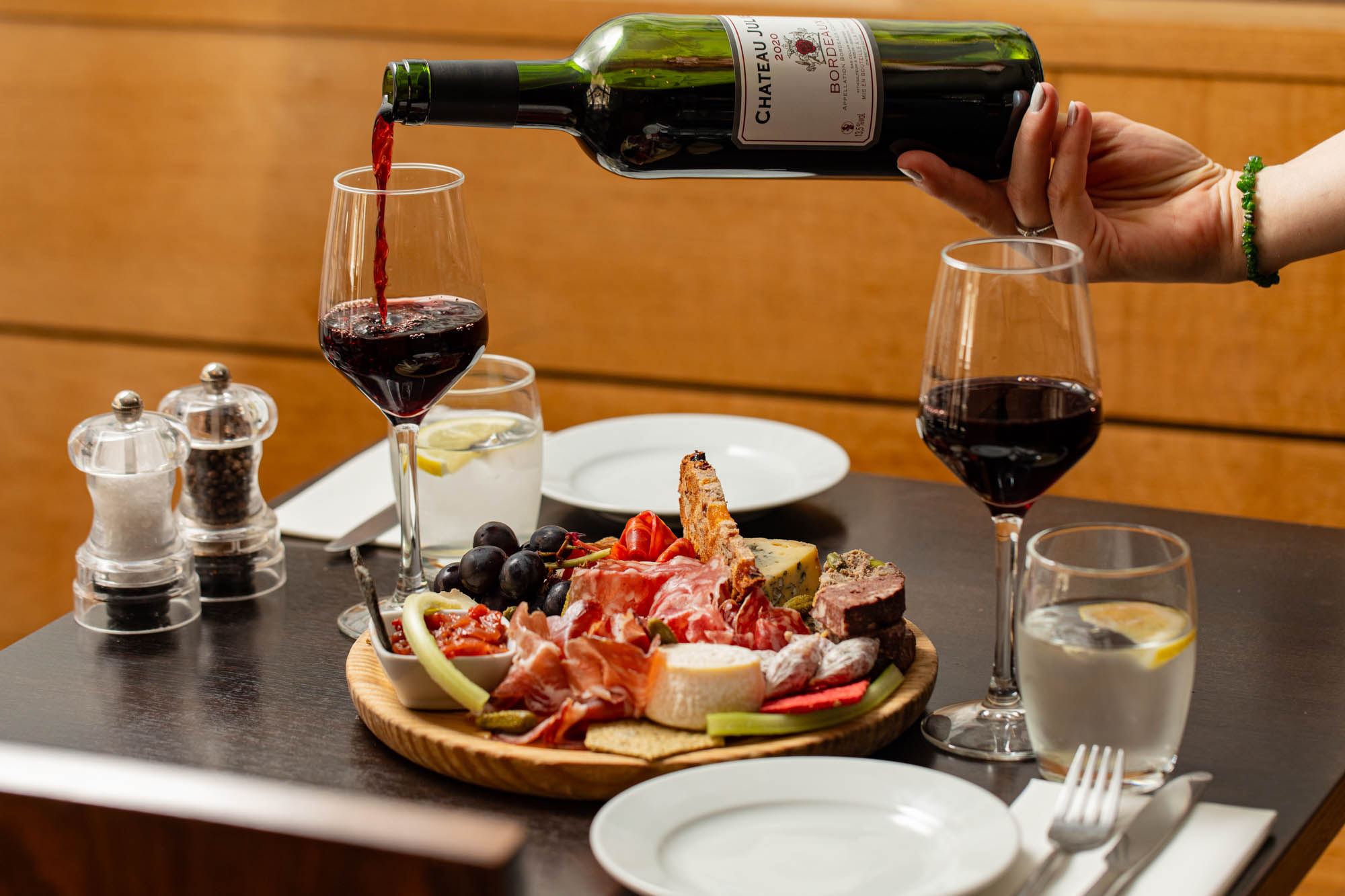 pouring red wine in the glass next to the charcoal boar on the Petit Pois