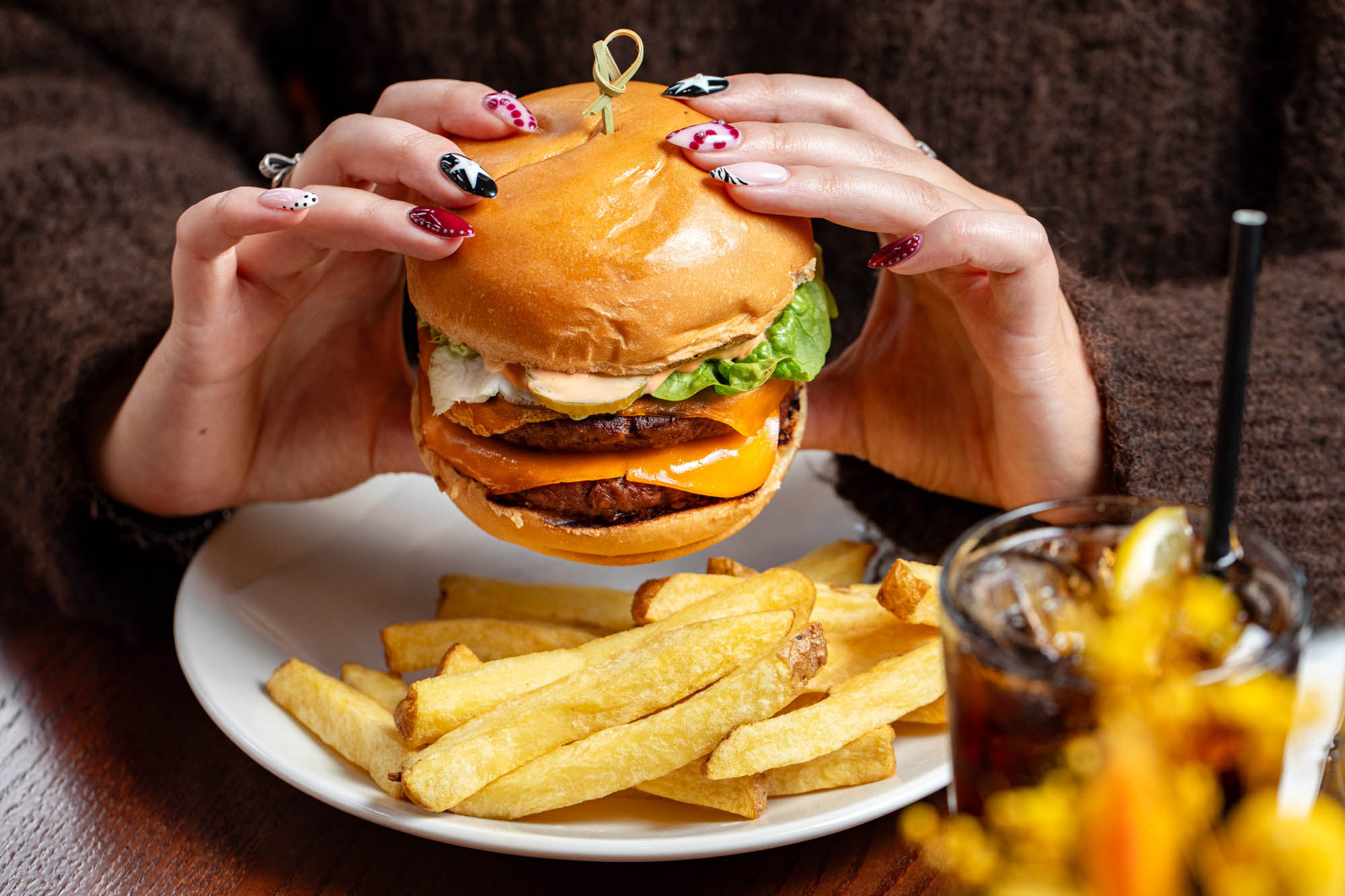hands holding burger served with chips