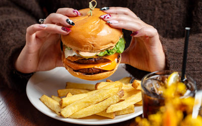 hands holding burger served with chips