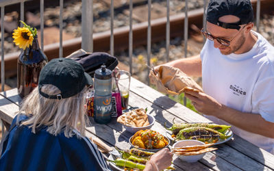 Diners eating outside at Sea Lanes Brighton with food provided by Wood X Coal