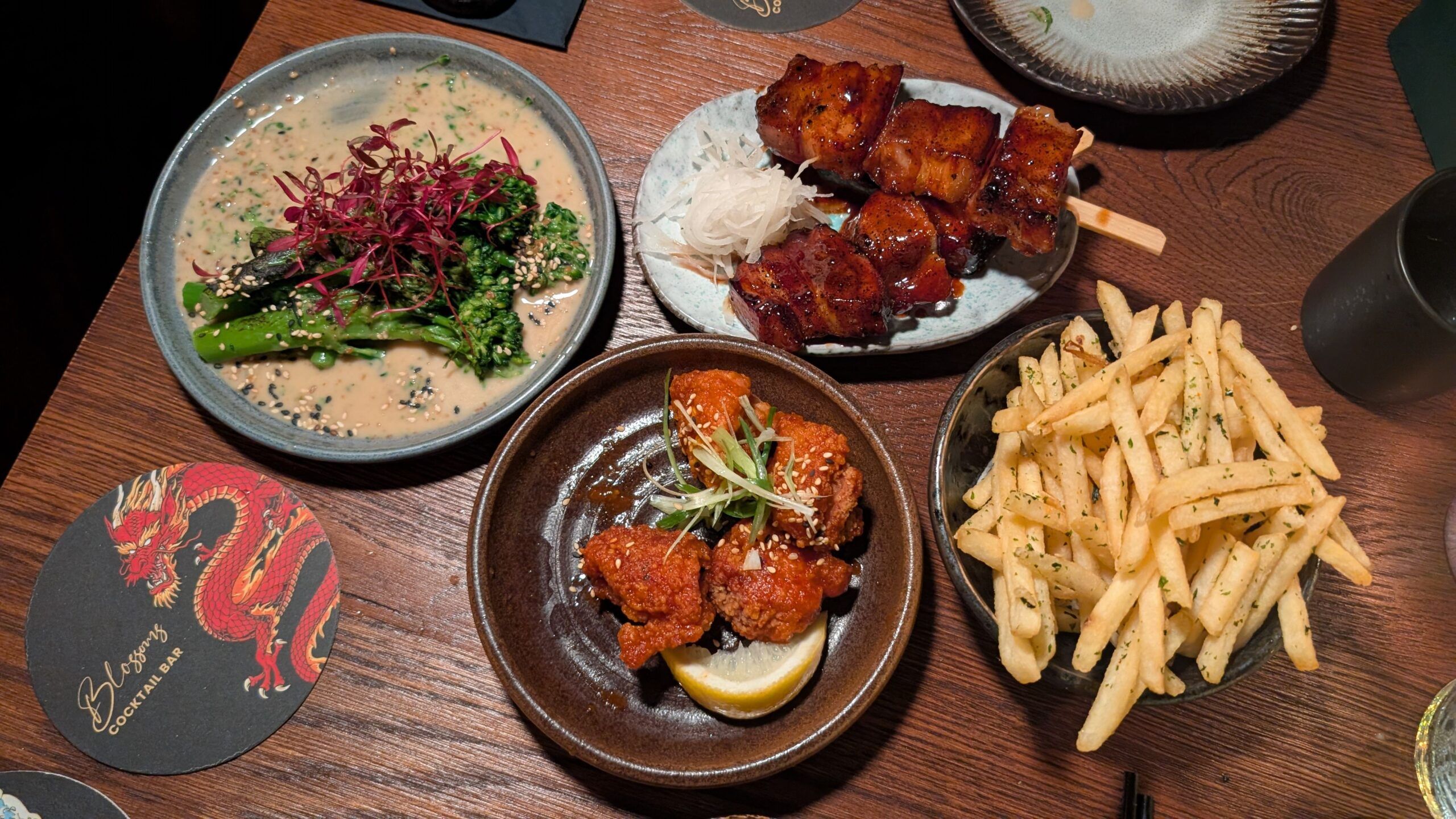 over head shot of the small plates including broccoli in a rich sesame sauce, spicy firecracker chicken, salty furikake-covered fries, crispy and light-as-air tempura prawns and sticky maple soy pork belly