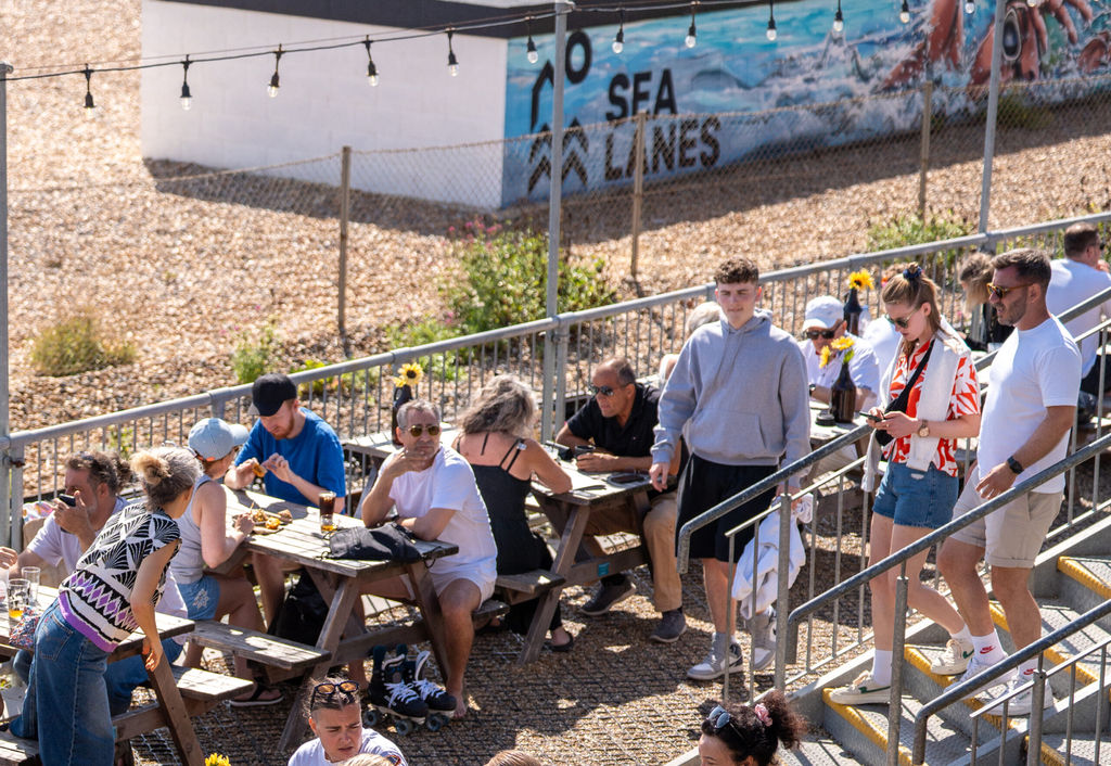 a picture from above at Sea Lanes Brighton. Diners sitting on pic nic benches, close to the pebbles at Sea Lanes Brighton