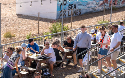a picture from above at Sea Lanes Brighton. Diners sitting on pic nic benches, close to the pebbles at Sea Lanes Brighton