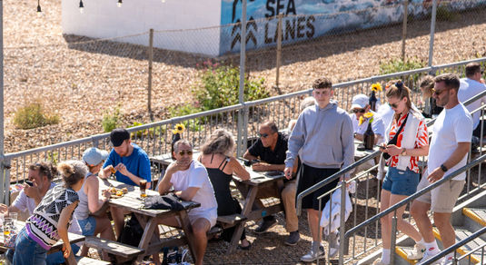 a picture from above at Sea Lanes Brighton. Diners sitting on pic nic benches, close to the pebbles at Sea Lanes Brighton