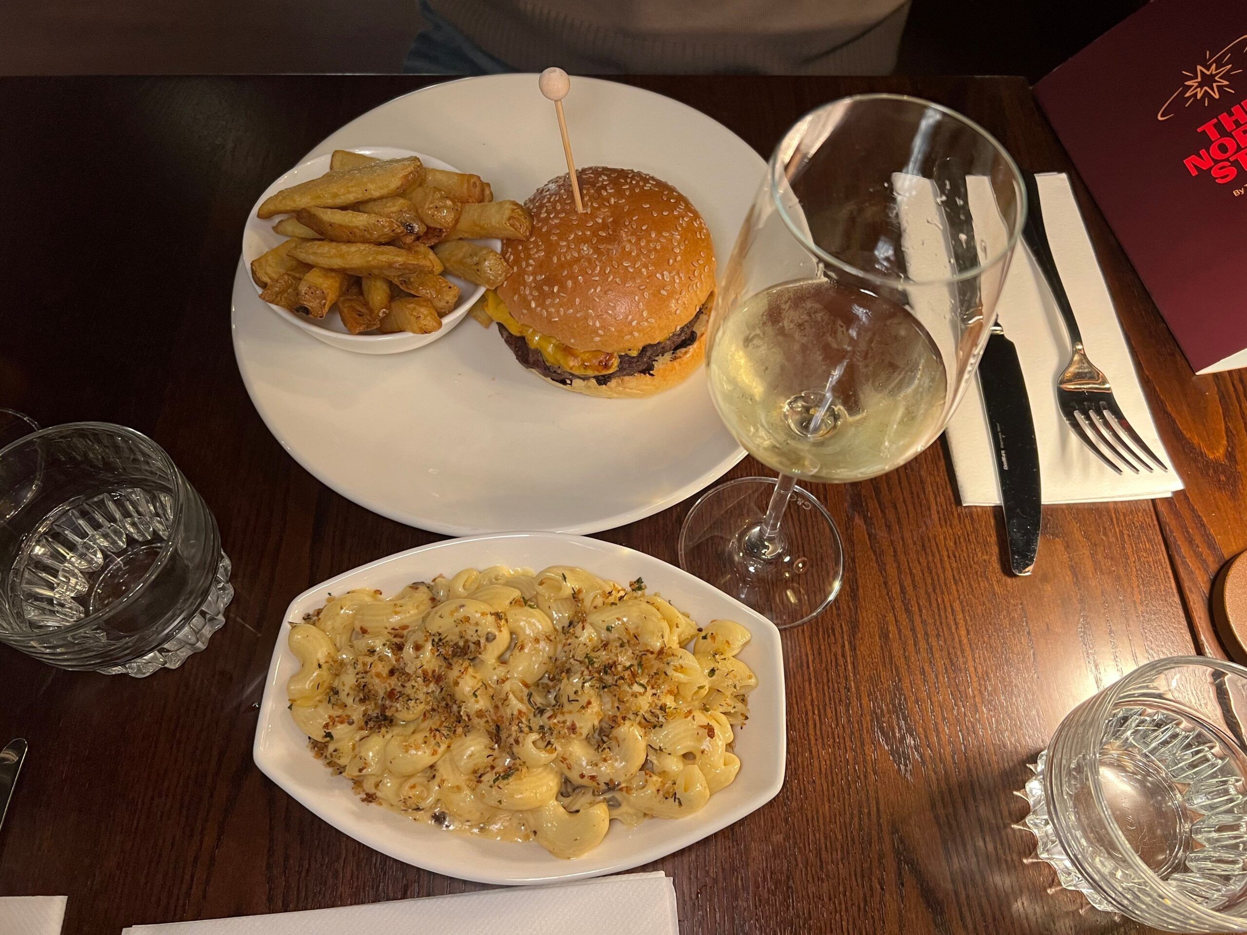 the north star burger served with chips on one plate and mac and cheese on another plate