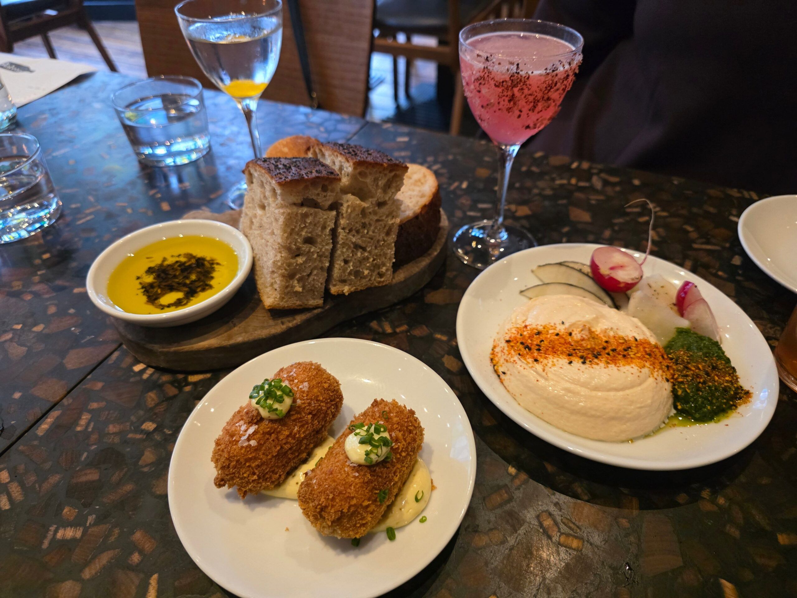 three startes on the table including croquettes, bread, olive oil, hummous 