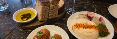 three startes on the table including croquettes, bread, olive oil, hummous