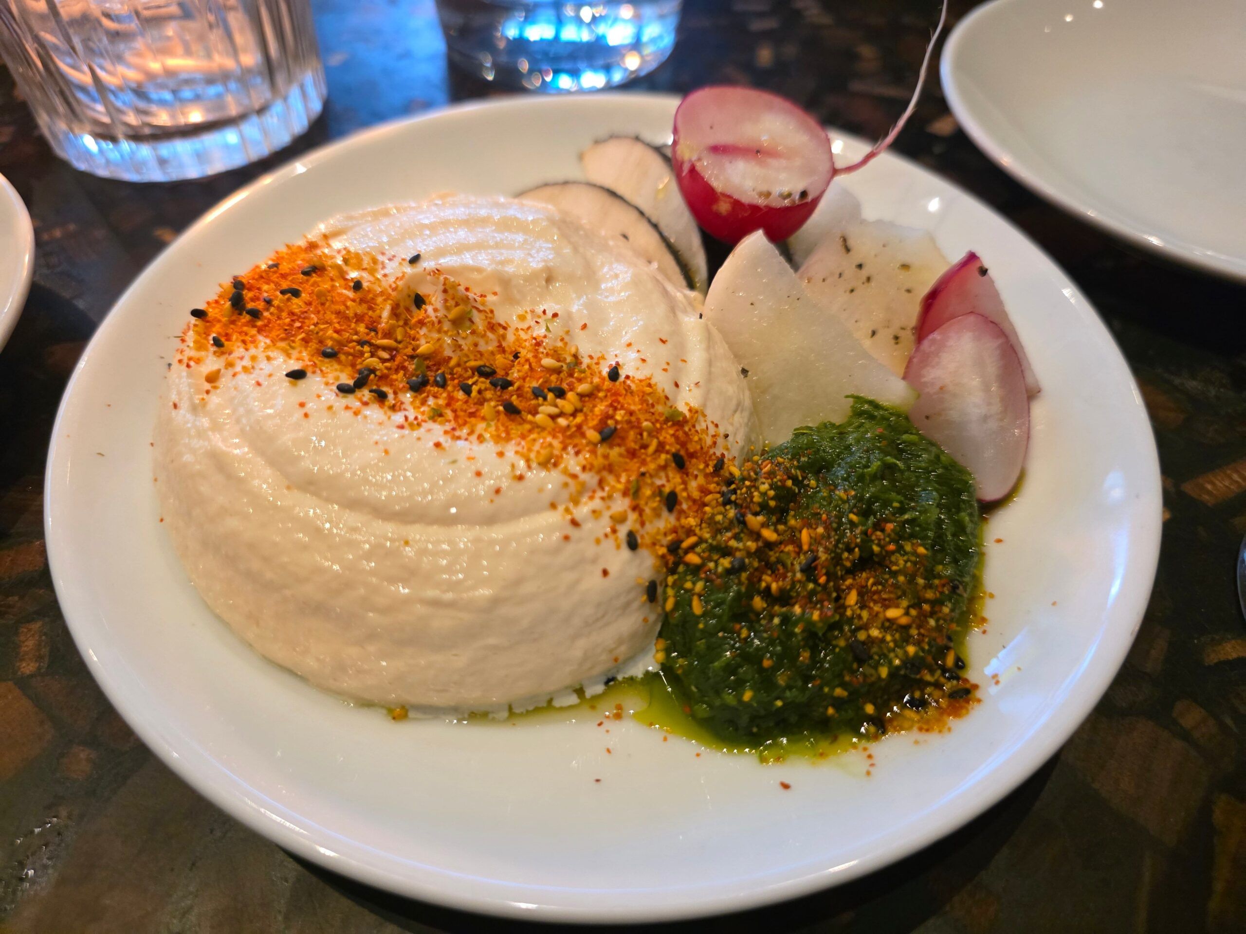 A large scoop of creamy hummus topped with spices and sesame seeds