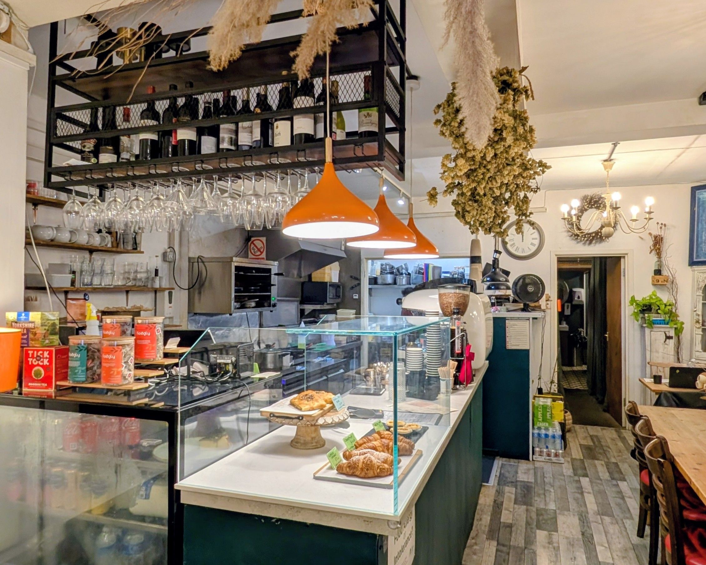 Interior of Meo Brighton café in Kemptown, with hanging wine rack, orange pendant lights and pastry counter.