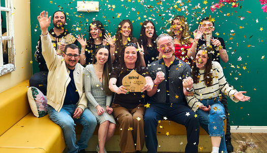 Best family friendly restaurant in Brighton and Hove. Jo & Co on Church Road celebrate their 2026 win for the most family friendly restaurant. the team celebrating their win, sat on a bench with a green backdrop.