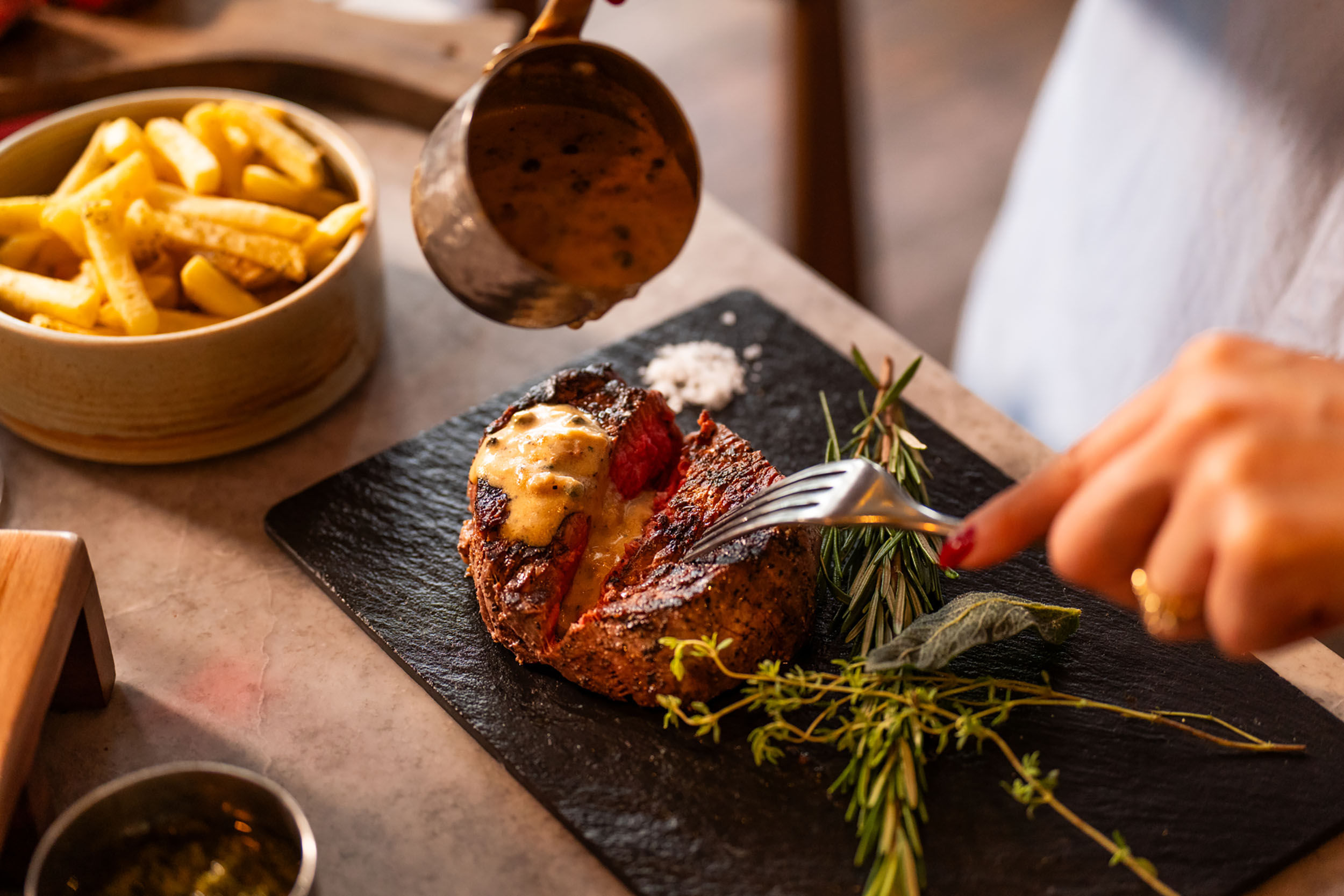 pouring gravy onto steak at Kindling