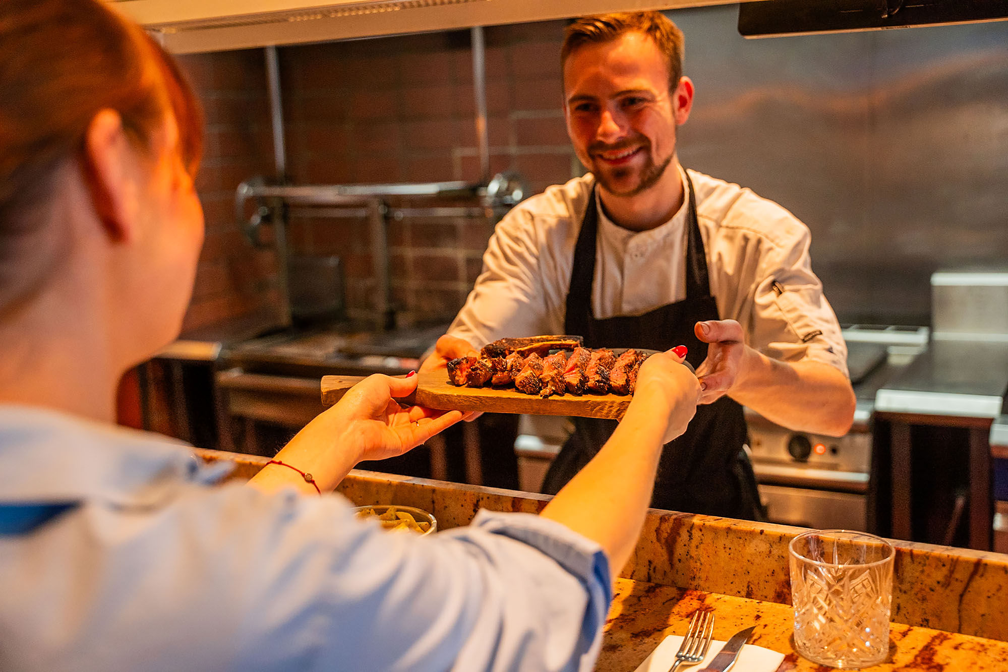chef giving meat platter to the waiter at Kindling Brighton