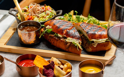 side shot of the burger cut in a half and served with chips and sauces
