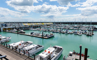 Brighton Marina. Several boats sit in the marina with the harbour wall behind. It's a sunny day with big white clouds.