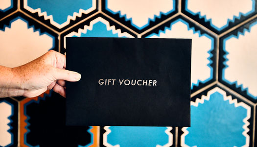 A gift voucher envelope in front of a blue tiled wall