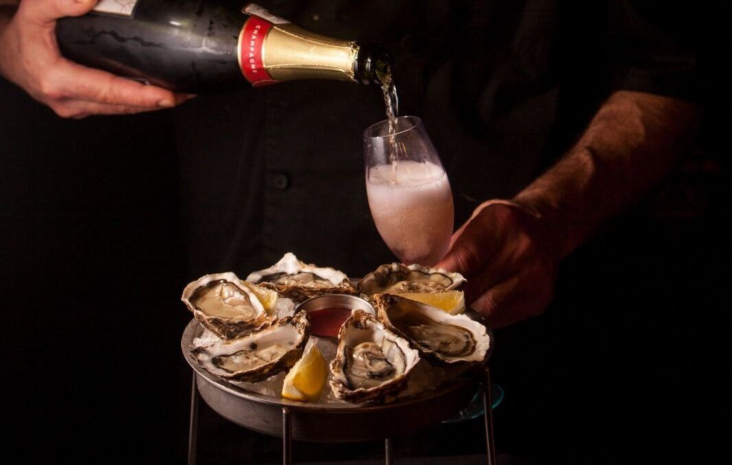 oysters on the table, and sparkling wine being poured in the glass 