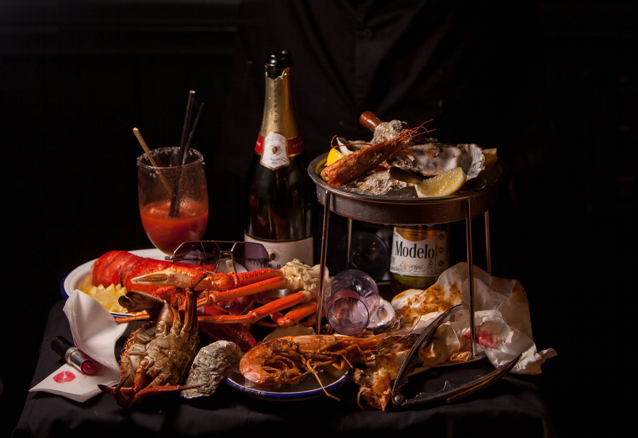 shot of the table populated with seafood boil dishes, bloody mary and sparkling wine