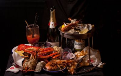 shot of the table populated with seafood boil dishes, bloody mary and sparkling wine