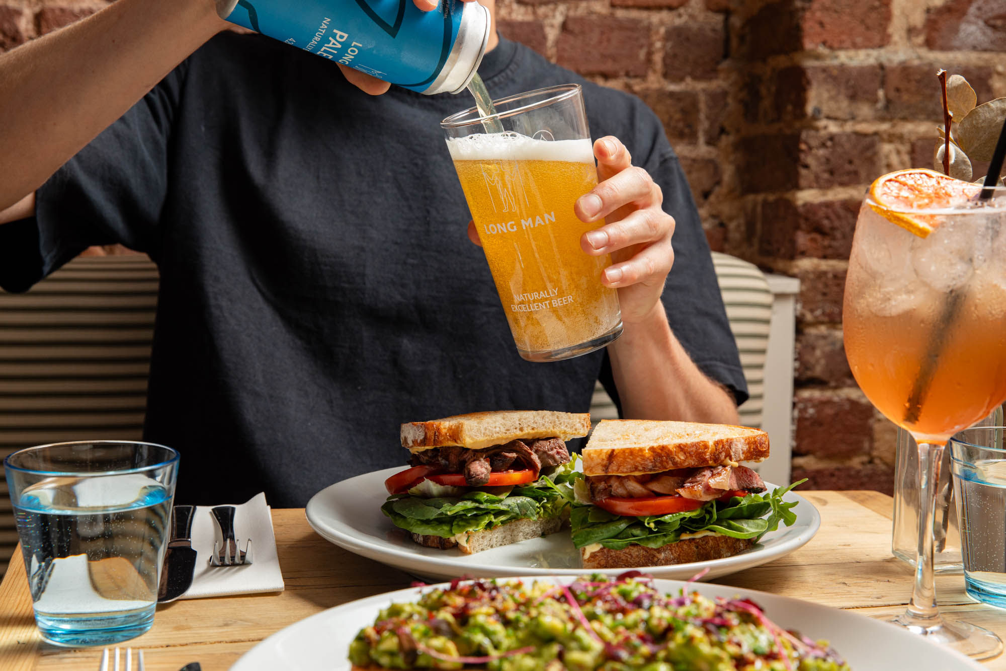 shot of person pouring beer into a glass which is above sandwiches at The Canopy