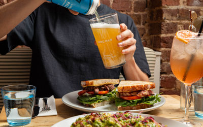 shot of person pouring beer into a glass which is above sandwiches at The Canopy