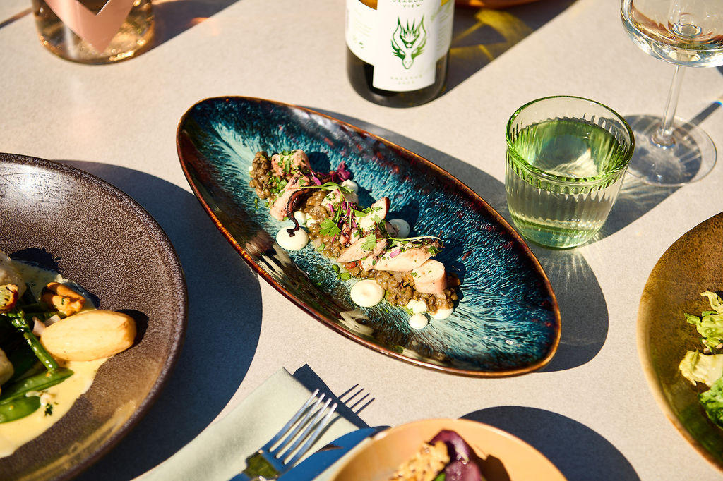 Octopus salad on a table outside with wine and summer dishes