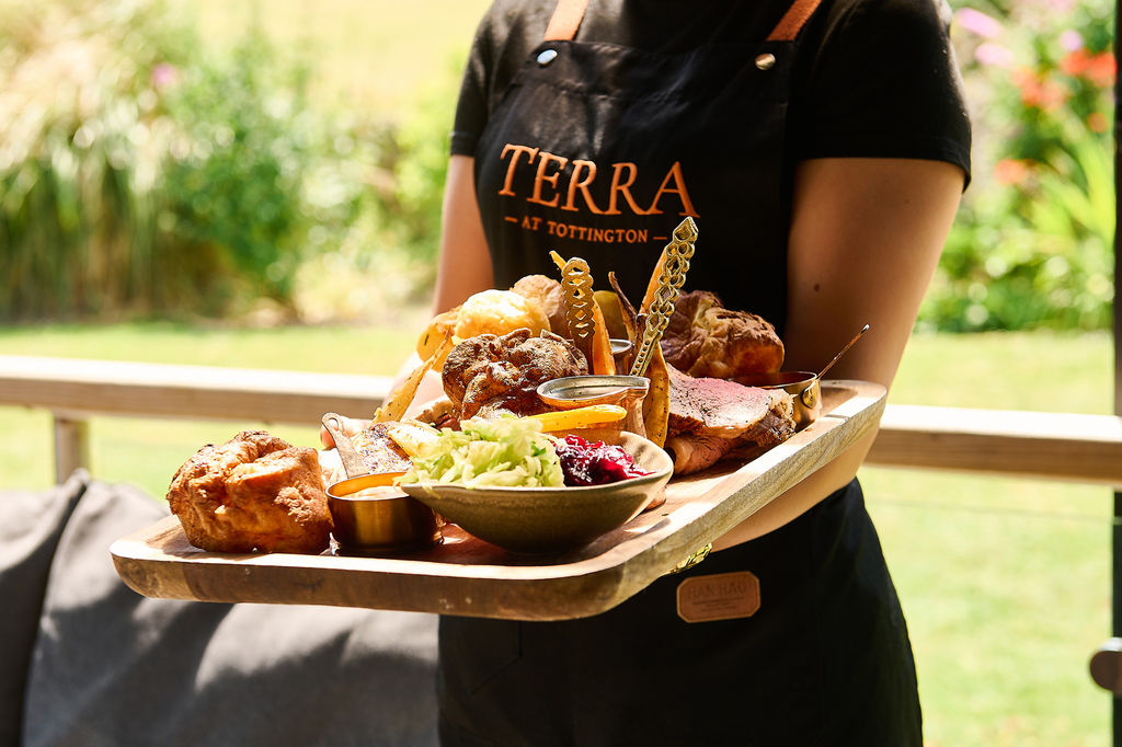 A sharing roast on a wooden board with a selection of meats, sides and yorkshire puddings