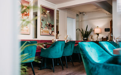 a stylish interior of a cafe. There is peacock blue seating, big modern art prtints on the wall. It looks inviting.