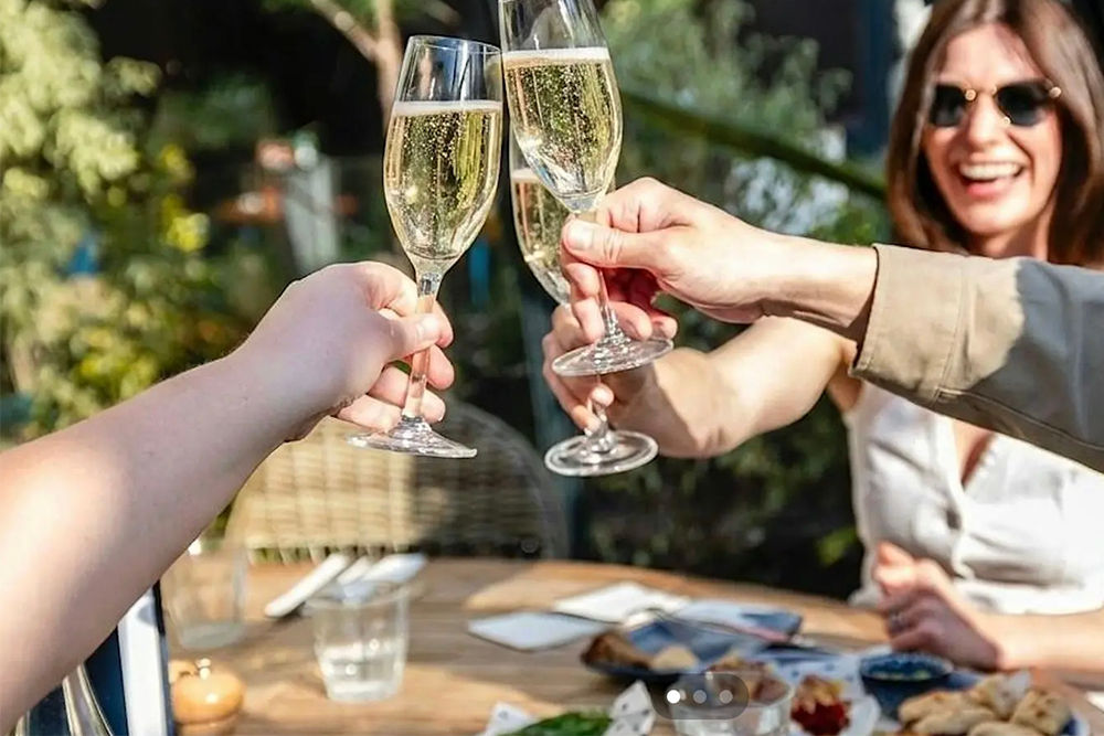 People enjoying a glass of proesecco in the Coppa Club Brighton alfresco dining igloo on a summer day