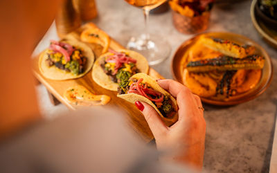 person holding tacos in the hand