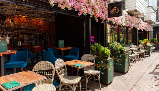 Exterior of Blossoms Cocktail Bar in Brighton on a sunny summer day with alfresco seating.