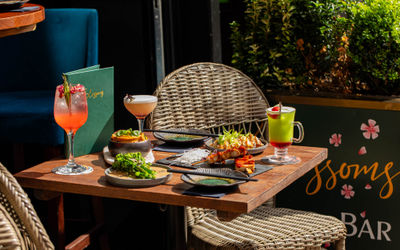 Small plates of food served on a table outside of Blossoms Cocktail Bar on a sunny summer day.