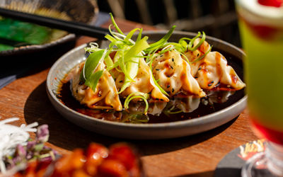 A dish of gyozas with spring onions sliced on top to garnish
