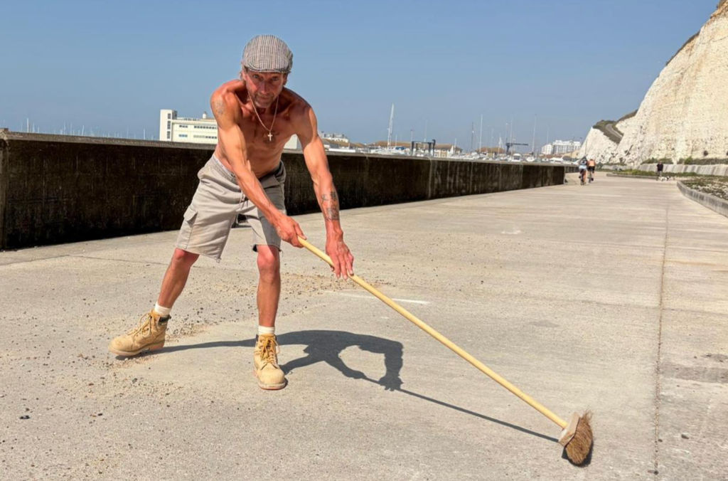 Brighton resident cleaning the beach of debris on a summer day