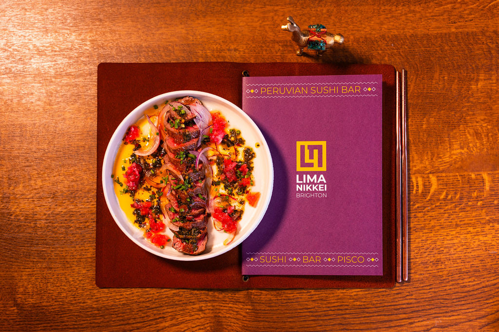 An overhead photo of a purple menu with a dish of vibrant Japanese-Peruvian cuisine.