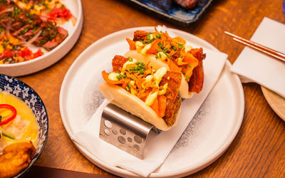 A white plate with two tacos on a metal stand with plates food in the background