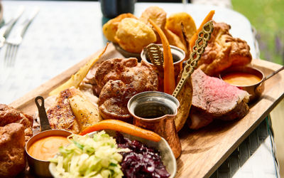 A sunday road sharing board with mixed meats, gravy, vegetables and large yorkshire puddings.